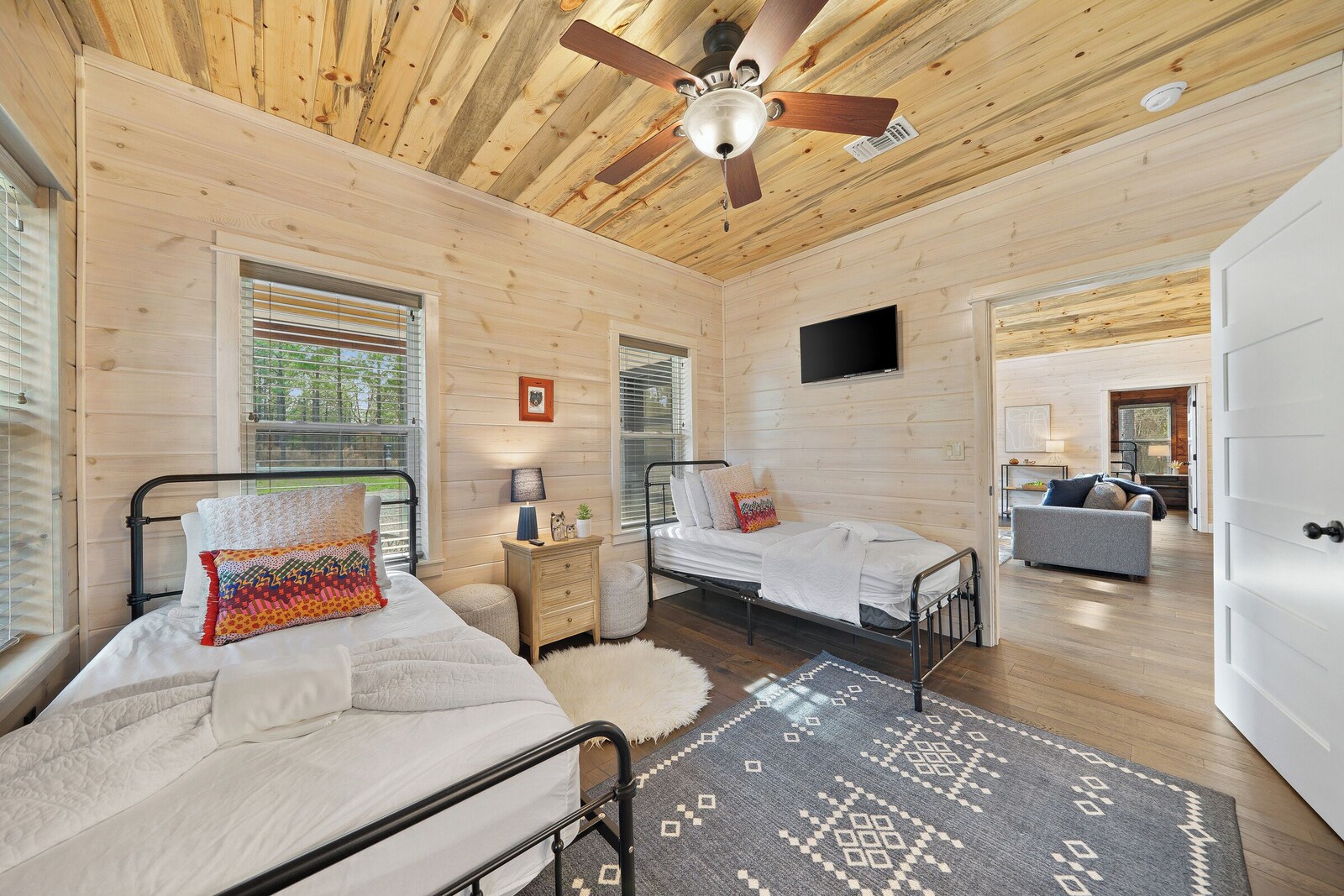 Twin bedroom with two beds, ceiling fan, and TV