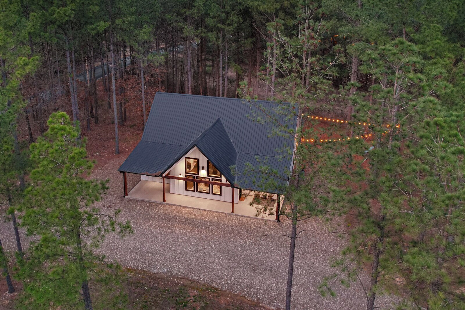 Cabin exterior with dark roof and gravel driveway