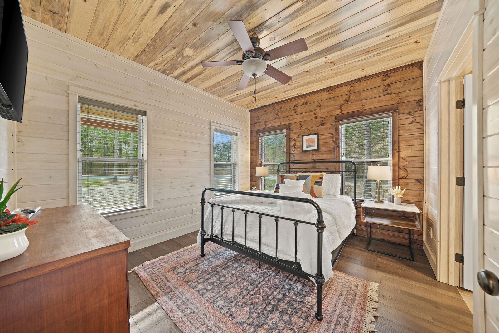 Bedroom with white bedding, nightstand lamp, and window blinds