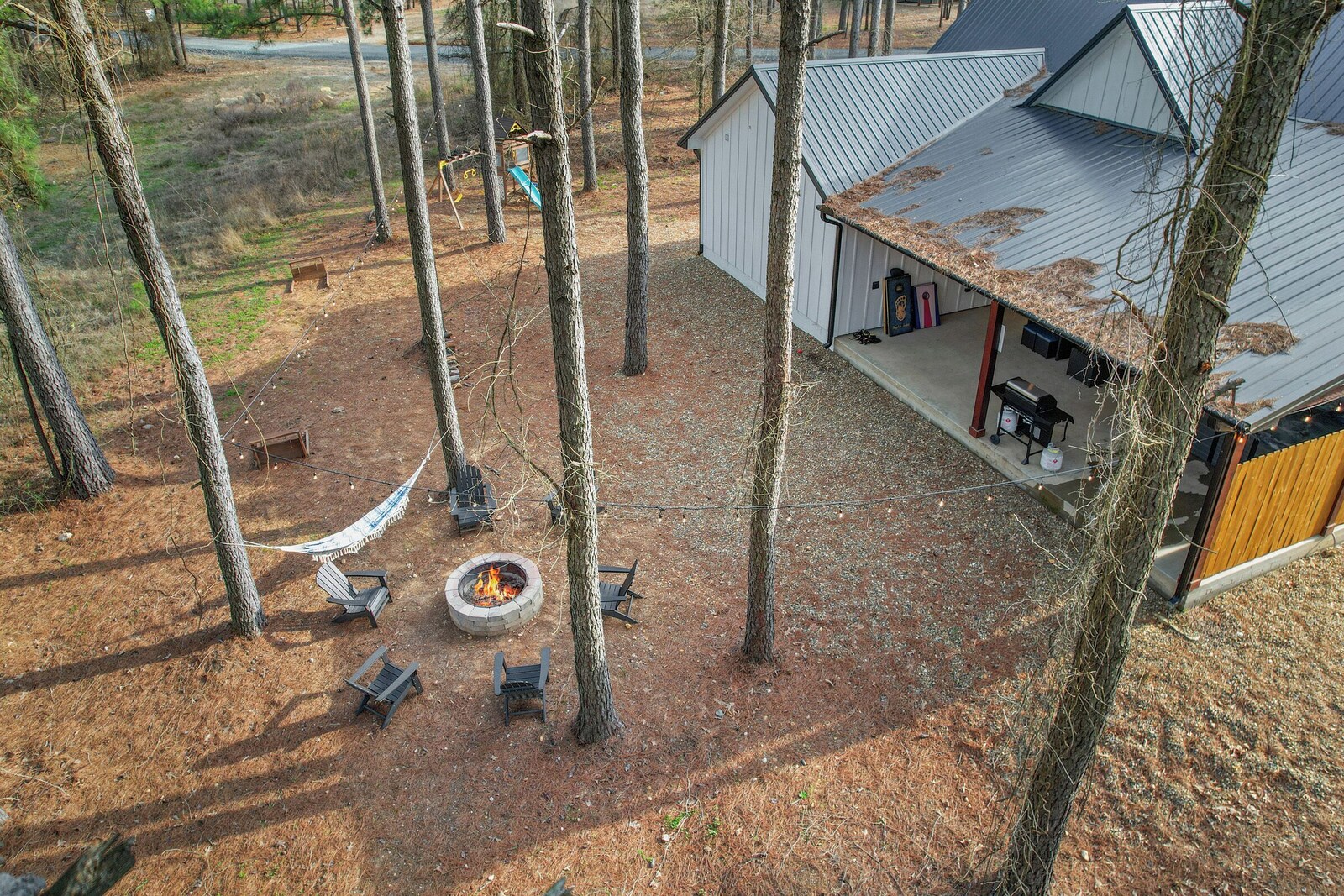 Cabin with fire pit, covered porch, and shed in the woods