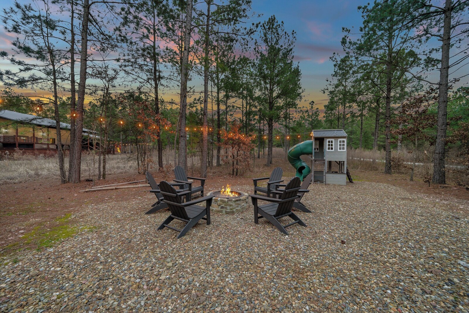Gravel patio with fire pit and two Adirondack chairs