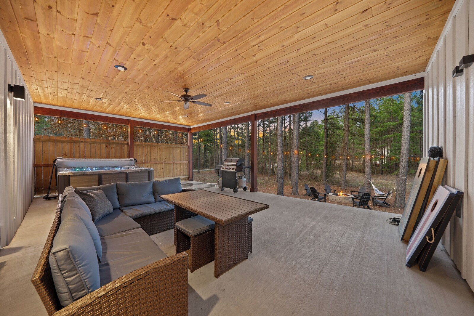 Covered outdoor living area with a large sofa, dining table, and grill