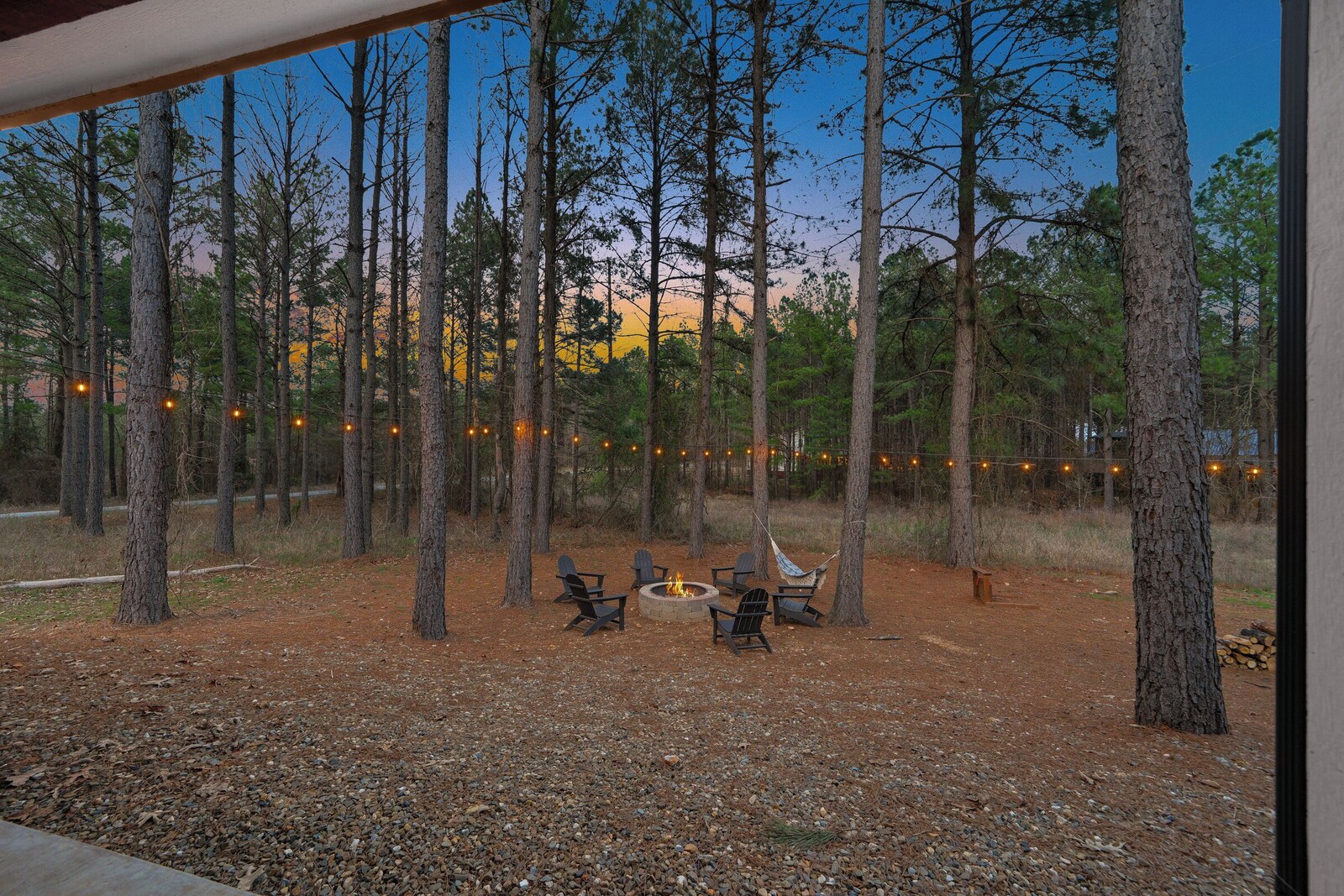 Fire pit ringed with chairs beneath the trees
