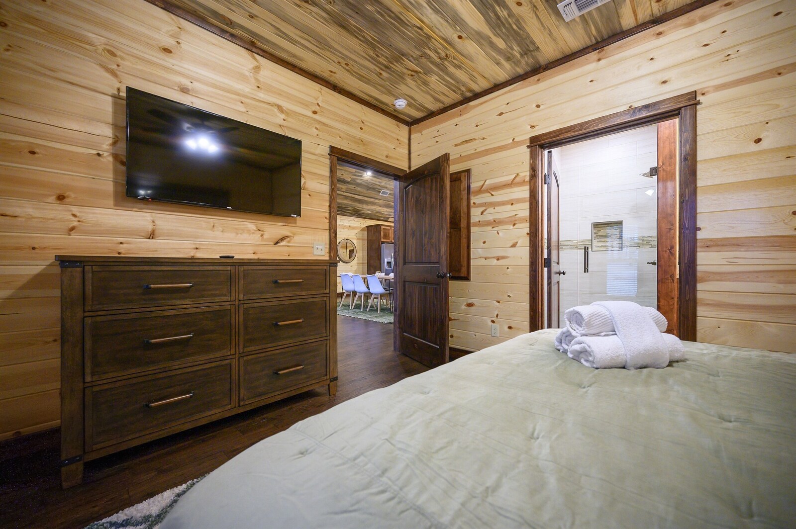 Emerald Escape bedroom with dresser and wall-mounted TV