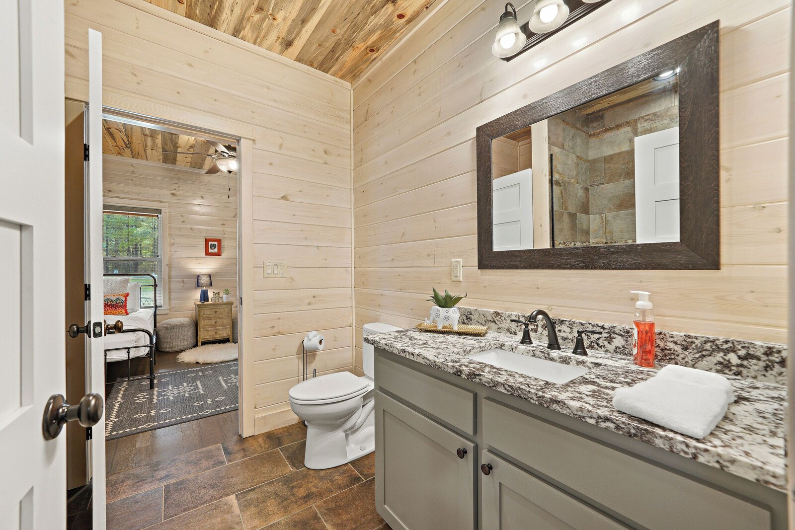 Bathroom with wooden walls, granite countertop, and large mirror