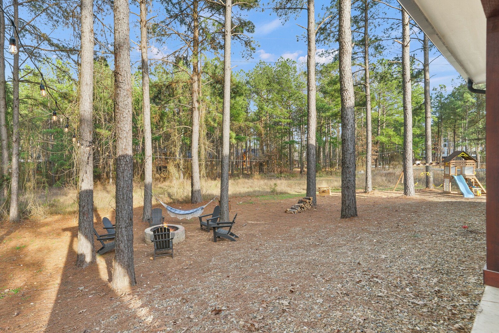 Forested campsite with hammock, fire pit, and picnic table
