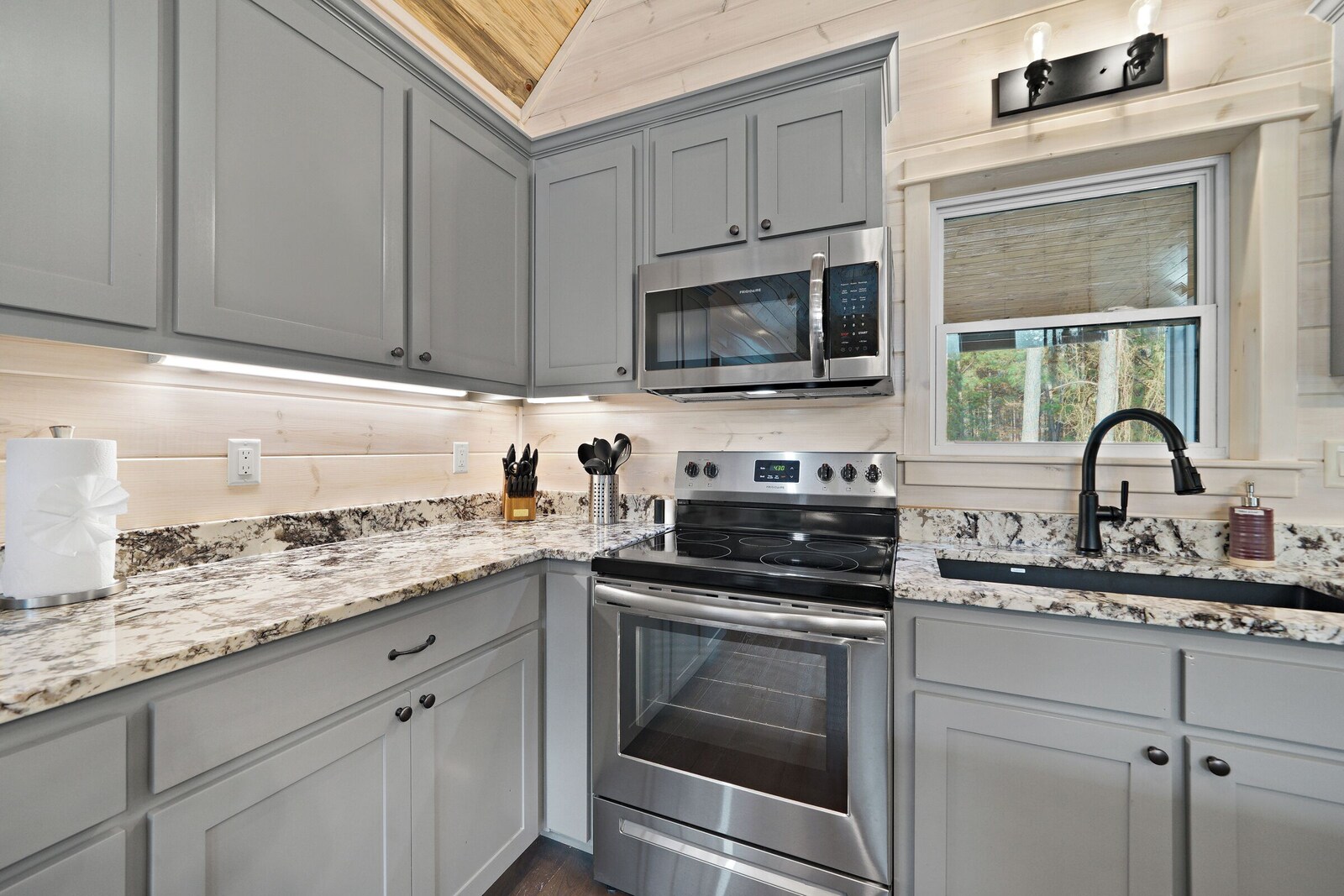 Kitchen with stainless steel oven, microwave, and granite countertop